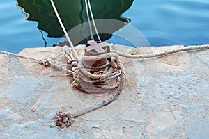 Rusted bollard holding boats in Greece harbor