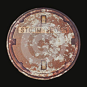 A Rusted Cast Iron Storm Sewer Cover Isolated on Black Background