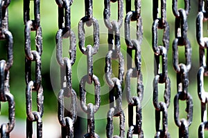 Rusted chain with black paint with Green nature background