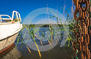 Rusted chain and boat on the lakeshore