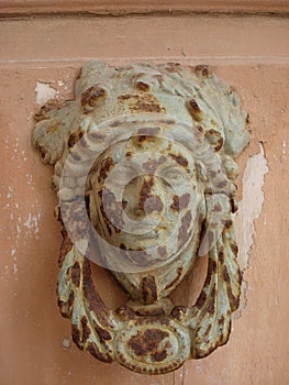 Rusted door knocker in the shape of a classical roman womans face