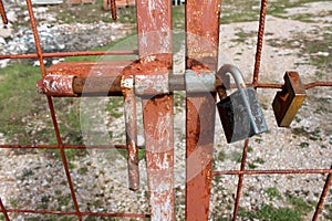 Rusted homemade metal fence with welded latch locked with padlock