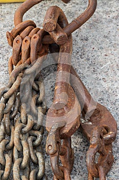 Rusted Hooks And Chains Hanging Against Cement