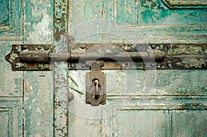 Rusted keyhole on green wooden door