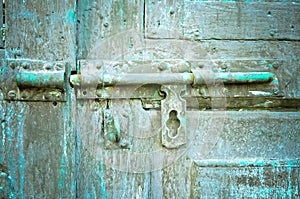 Rusted keyhole on green wooden door