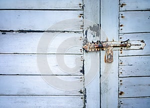 Rusted keyhole on white wooden door