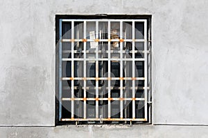 Rusted metal bars protection covering old broken window with safety glass and dilapidated cracked wooden frame