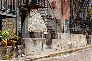 Rusted metal fire escape stairs and crumbling concrete steps at the back side of an old apartment building