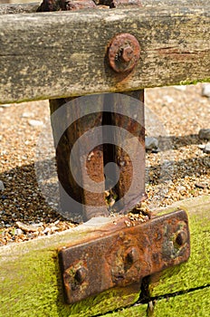 Rusted metal plates hold a wooden groyne together