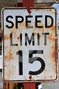 Rusted metal speed limit sign affixed to a tall metal pole in a rural area