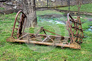 Rusted old harrows on green grass