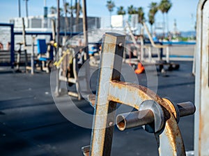 Rusted outdoor weight rack empty at public gym with workout equipment in background