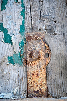 Rusted and painted old clasp with connector and boltt attached to wood boards with scraps of paint