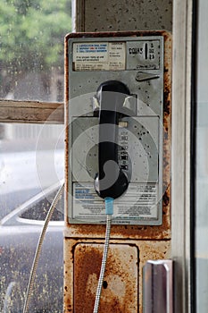 Rusted push-button payphone in glass booth