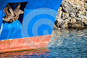 Rusted rugged Anchor on blue fishing ship