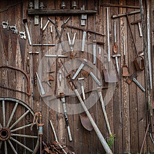 Rusted tools hung on side of old weathered wood barn.