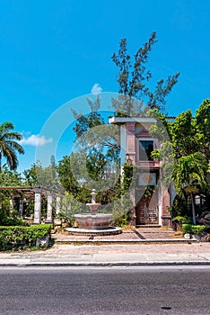 Rustic abandoned Spanish style residential bungalow and fountain at roadside