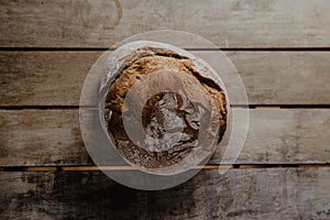 Rustic bread, covered in flour, on wooden table photo