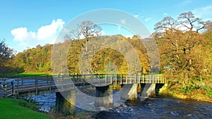Rustic autumn scene of a stone bridge arching over the Wharfe River.