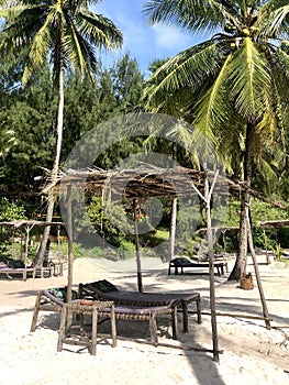 Rustic beach cabana and loungers on tropical beach