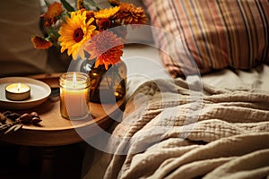 A rustic bedside table, a candle and a cozy blanket. Boho home decor. Ethnic bedroom interior. Generative AI