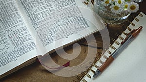 Rustic Bible on a Wooden Background with Notepad and Flowers