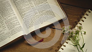 Rustic Bible on a Wooden Background with Notepad and Flowers