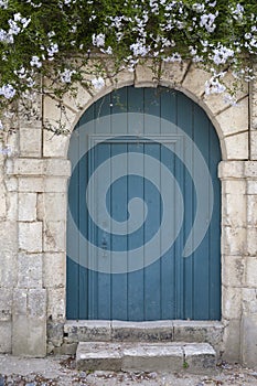 Rustic blue wooden door with white flowers above