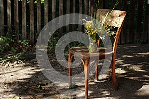 Rustic bouquet of wild flowers on old wooden chair in summer day