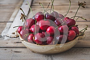 Rustic bowl with fresh red cherries on an old rustic wooden table