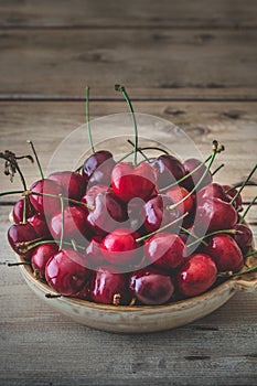 Rustic bowl with fresh red cherries on an old rustic wooden table