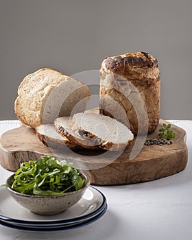 Rustic bread on a cutting board with bowl full of rucola