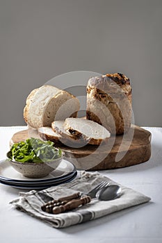 Rustic bread on a cutting board with bowl full of rucola