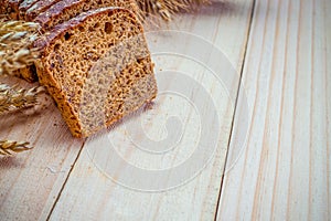 Rustic bread. Fresh loaf of rustic traditional bread with wheat grain ear or spike plant on wooden texture background