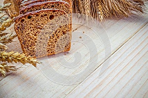 Rustic bread. Fresh loaf of rustic traditional bread with wheat grain ear or spike plant on wooden texture background