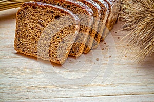 Rustic bread. Fresh loaf of rustic traditional bread with wheat grain ear or spike plant on wooden texture background