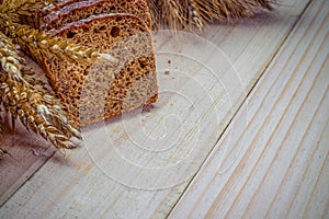 Rustic bread. Fresh loaf of rustic traditional bread with wheat grain ear or spike plant on wooden texture background. Rye bakery