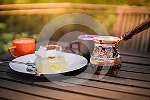 Rustic breakfast. Wooden coffee table with coffee cups, cezve, lake Bled cream cake