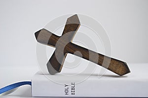 Rustic brown wood cross on its edge on top of the bible