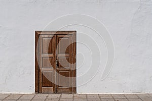 Rustic brown wooden entrance door in white wall