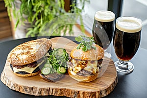 Rustic burger and beer setup with fresh greenery on wooden table