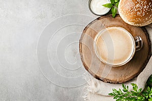 Rustic burger and beer setup with fresh greenery on wooden table