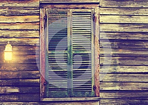 Rustic cabin window with closed shutters and porch light