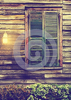 Rustic cabin window with closed shutters and porch light