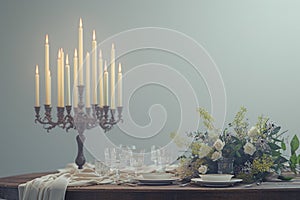 A rustic candlelit dinner setting featuring an antique wooden table set against a stark white background