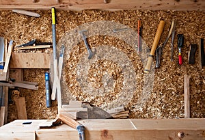 Rustic carpentry workshop filled with wood shavings, hand tools on the wall, and a sturdy wooden workbench. Generative AI
