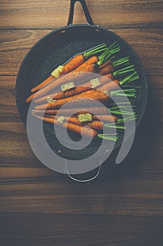 Rustic carrots in a pan on wood