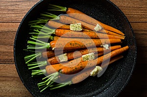 Rustic carrotts in a pan with butter on wood