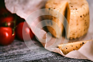 Rustic cheese with herbs on paper and tomatoes