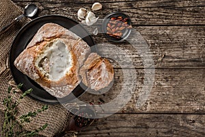 Rustic chicken soup with mushrooms in bread with spices on rustic wooden background.